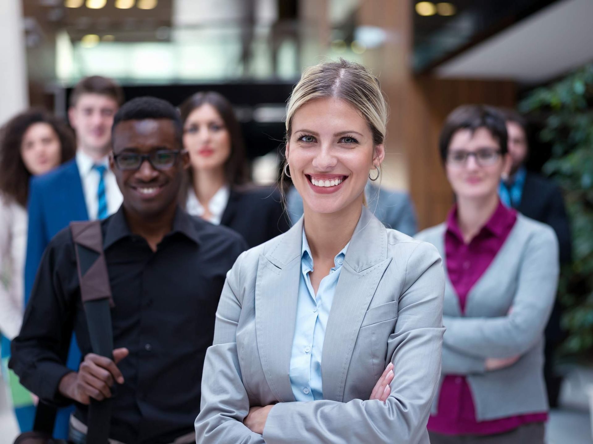 Een groep van negen personen in zakelijke kleding viert feest met opgeheven armen.