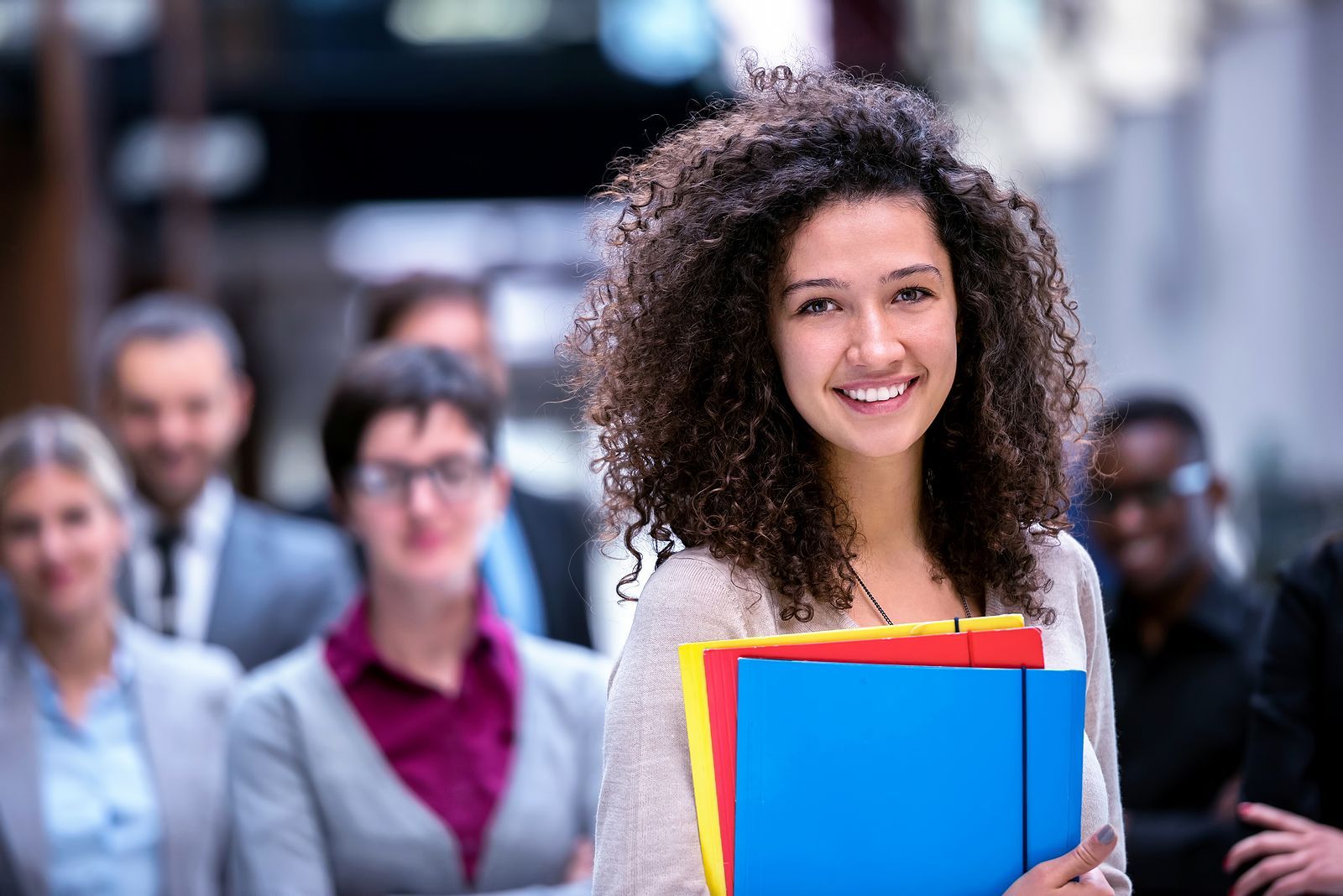 Een groep van negen personen in zakelijke kleding viert feest met opgeheven armen.