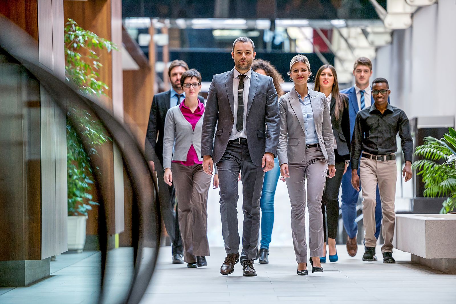 Een groep mensen in zakelijke kleding viert feest met opgeheven armen.