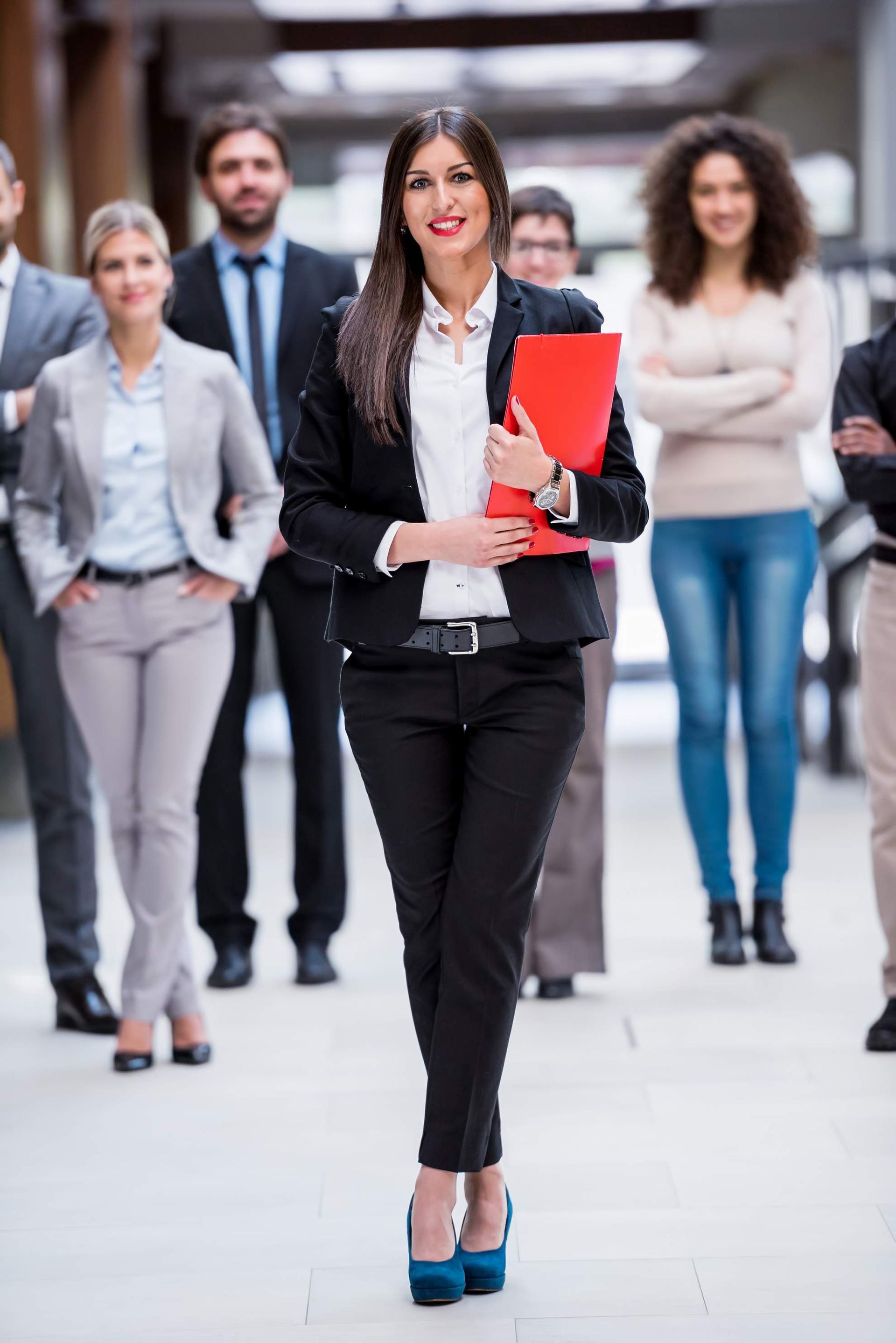 Een groep van negen personen in zakelijke kleding viert feest met opgeheven armen.
