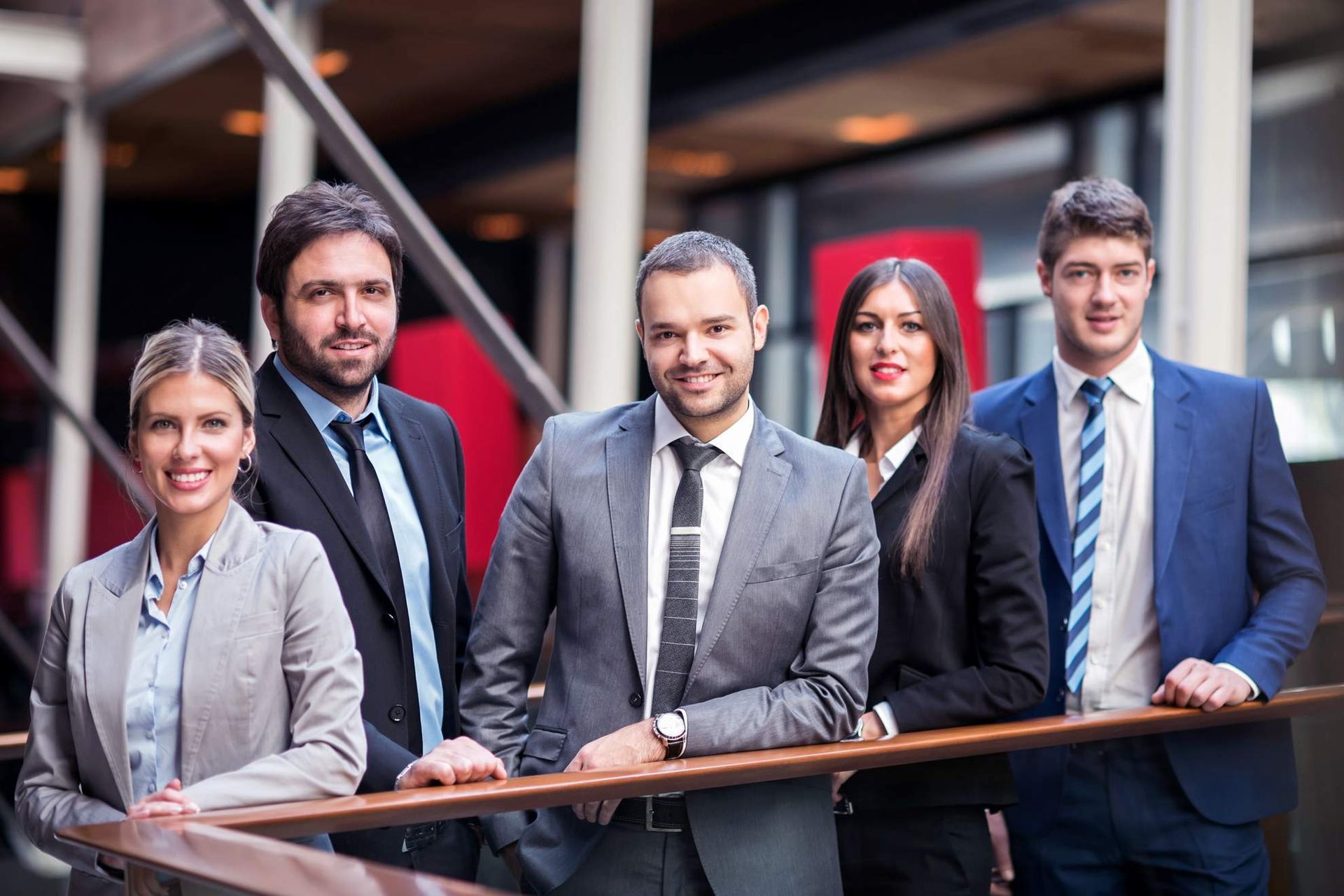 Een groep van negen personen in zakelijke kleding viert feest met opgeheven armen.