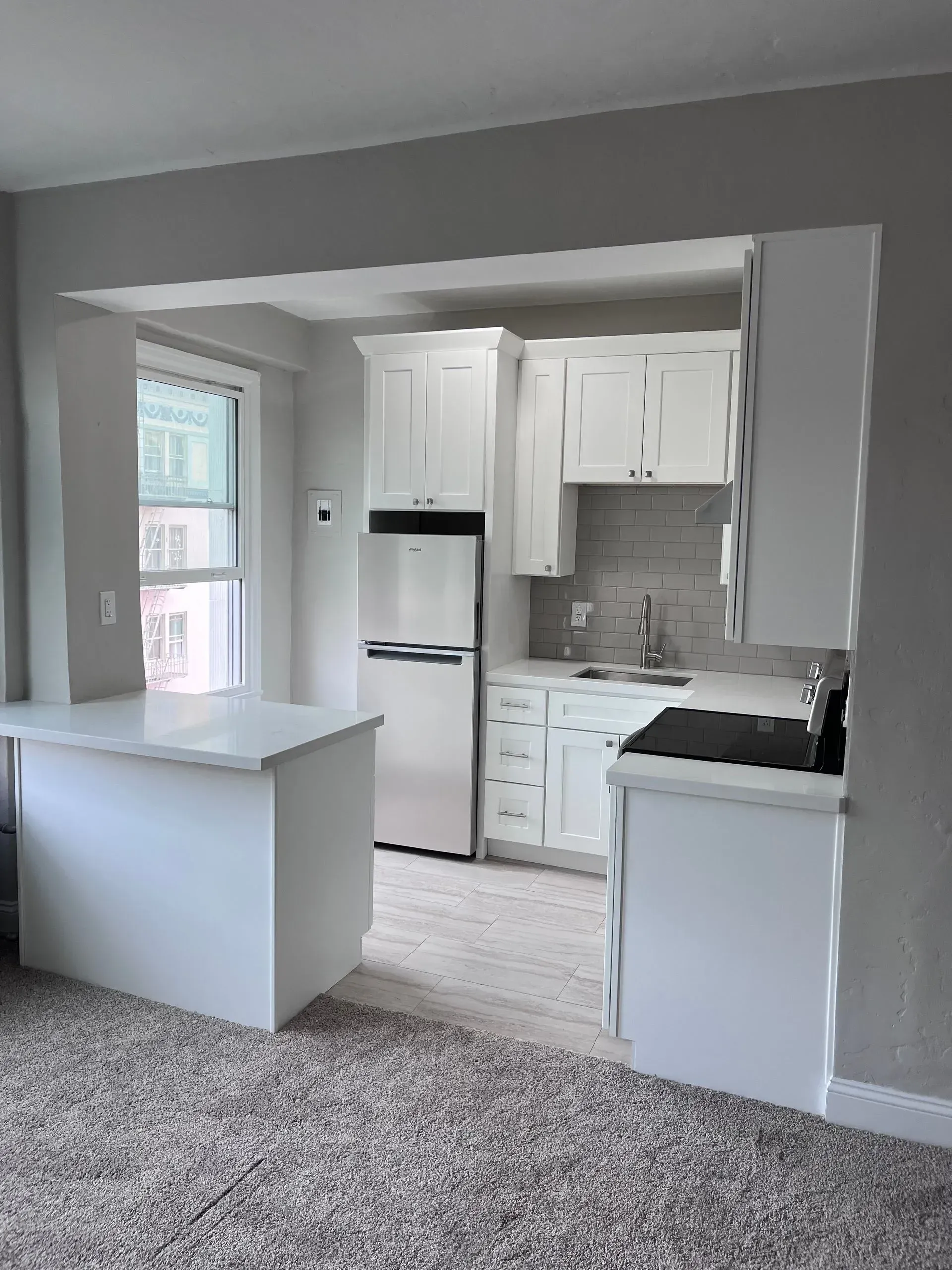 White kitchen with cabinets, appliances, and a countertop island.