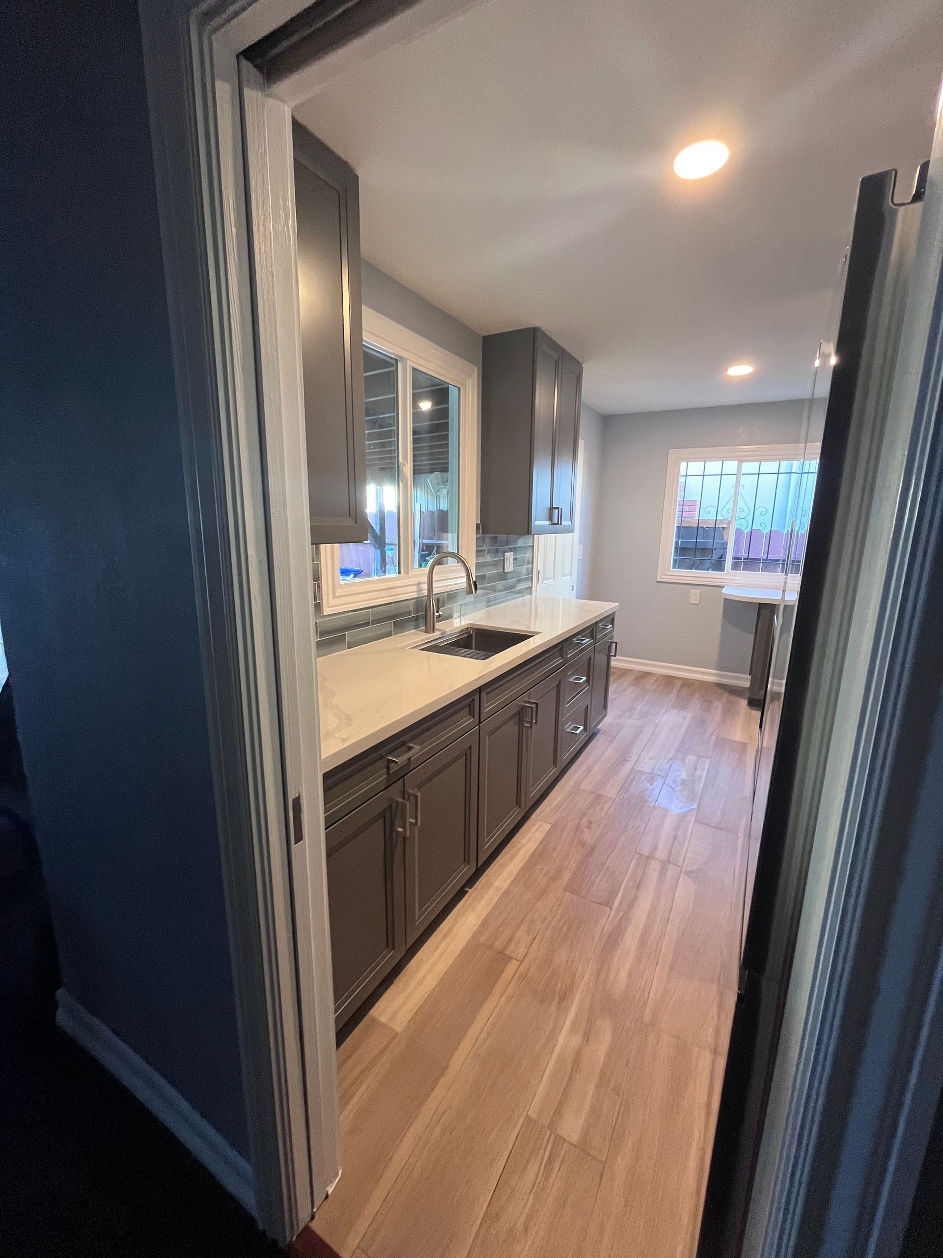 Gray kitchen with white countertops and light wood floors.