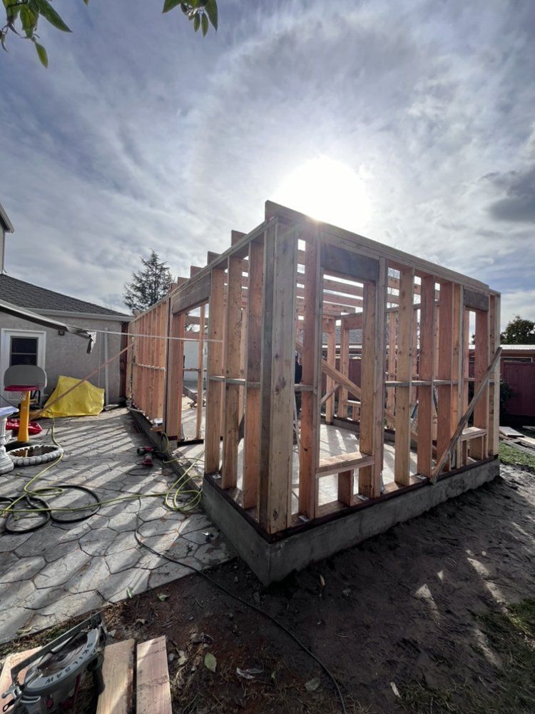 Wooden frame of a building under construction, outdoors with a sunny sky.