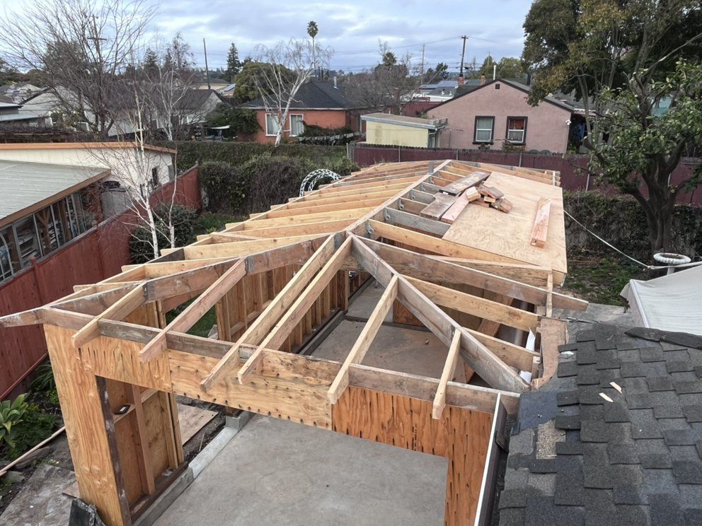 Garage roof under construction, wood framing visible. Overcast day, residential setting.