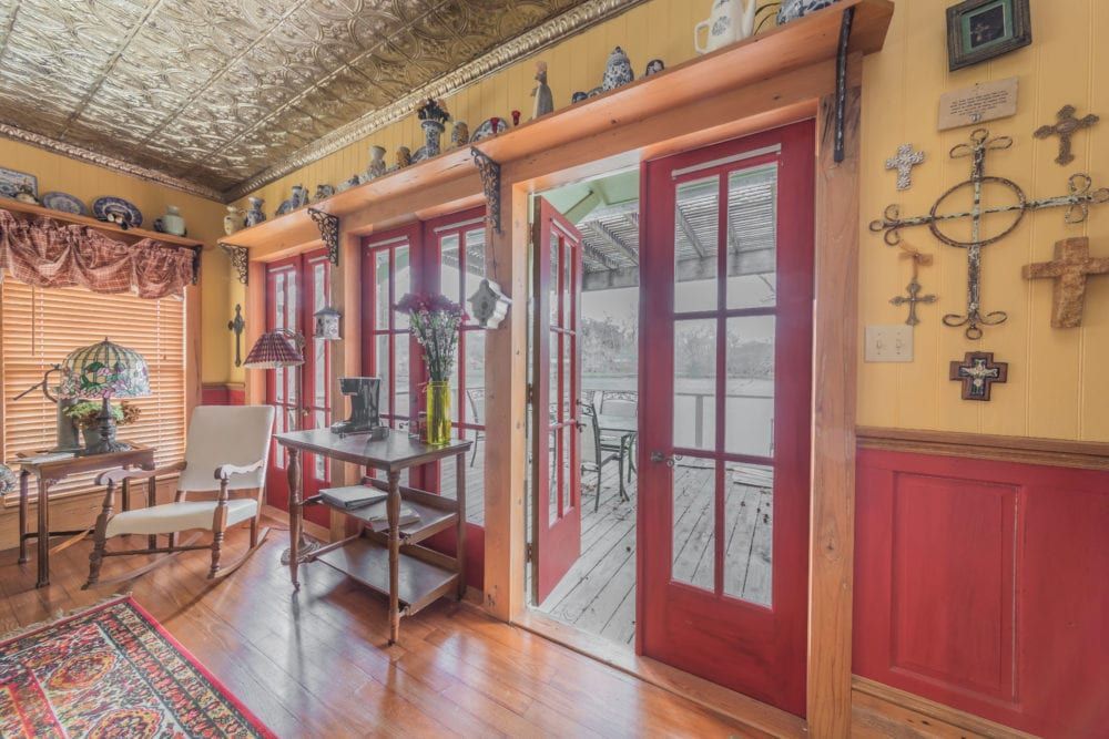 A living room with a rocking chair , table , and sliding glass doors leading to a porch.
