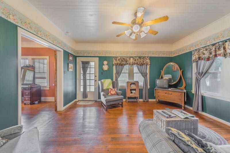 A living room with a ceiling fan , couch , chair and television.