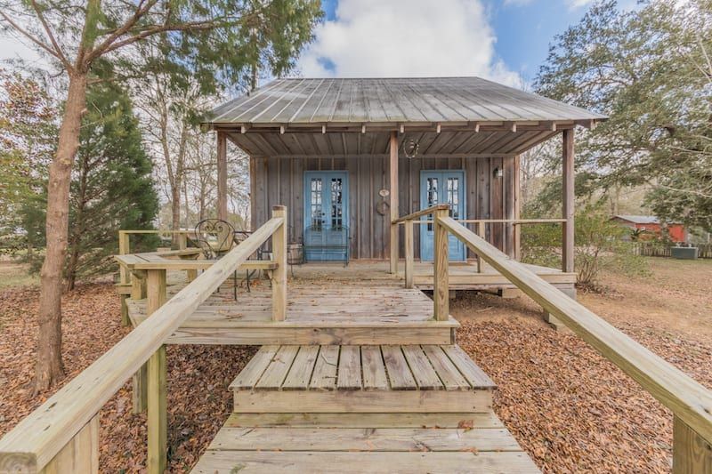 A small house with a wooden deck and stairs leading to it.