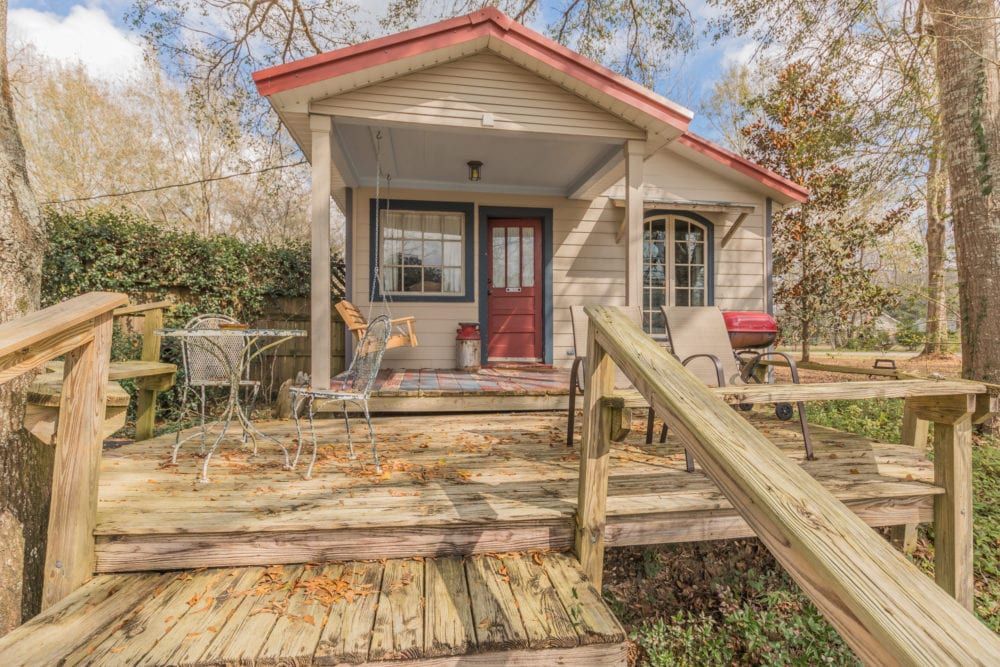 A small house with a porch and stairs leading up to it.