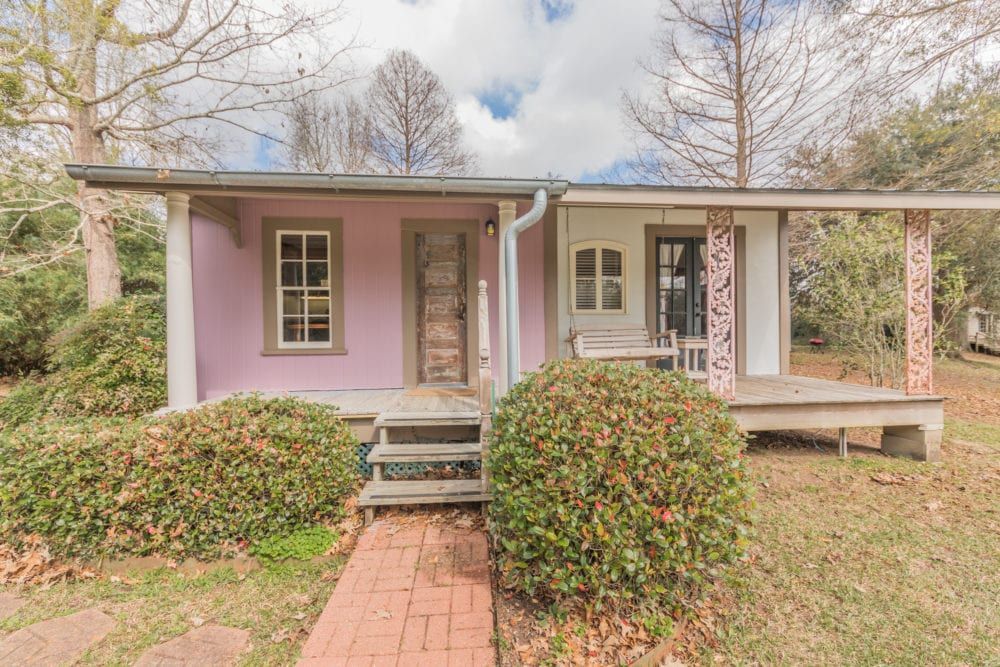 A small purple house with a porch and stairs is for sale.