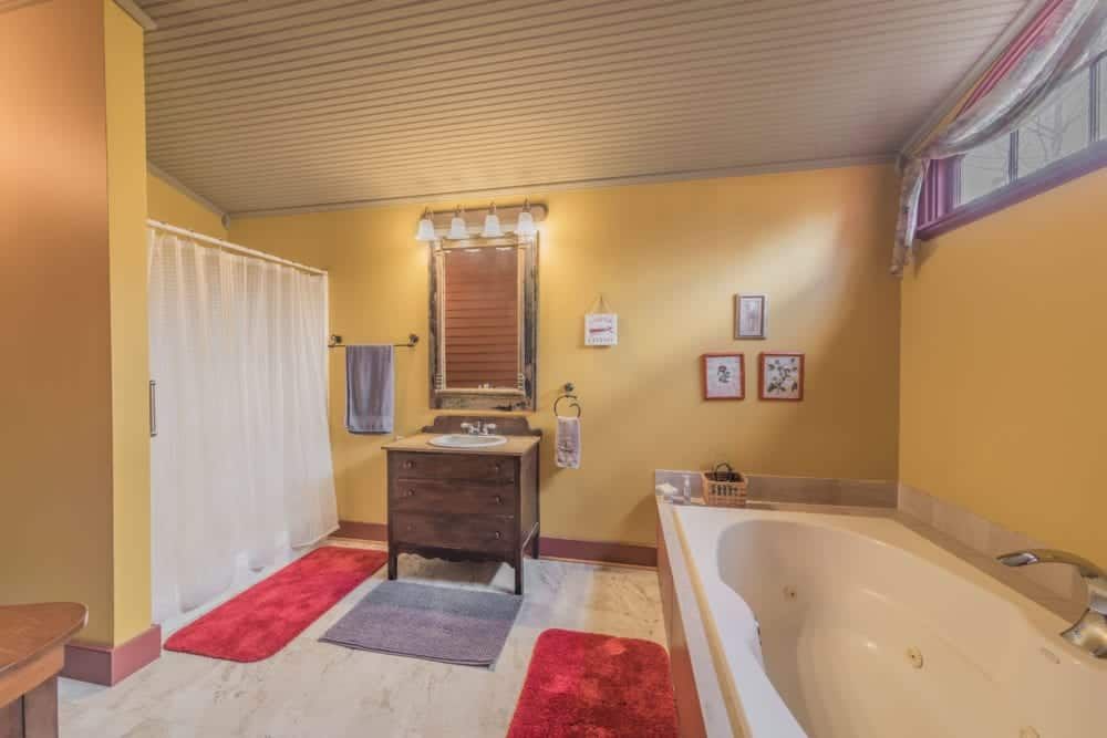 A bathroom with a tub , sink , mirror and shower curtain.