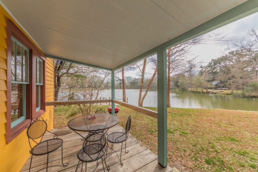 A porch with a table and chairs overlooking a lake.