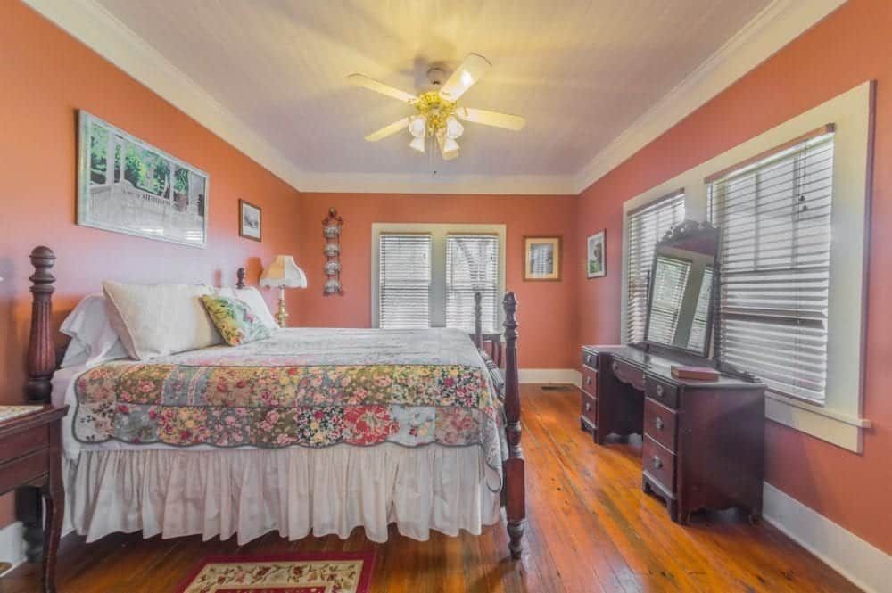 A bedroom with two beds , a dresser , a mirror and a ceiling fan.