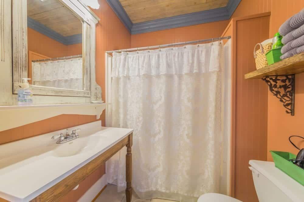 A bathroom with a sink , toilet , mirror and shower curtain.