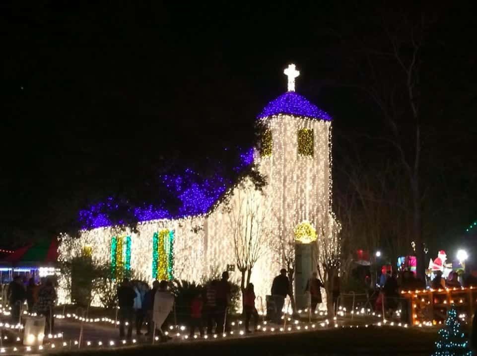 A church is lit up with christmas lights at night