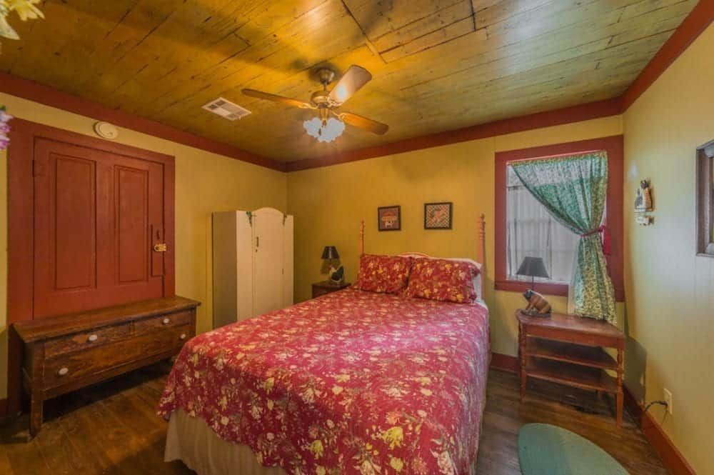 A bedroom with a bed , nightstand , dresser and ceiling fan.