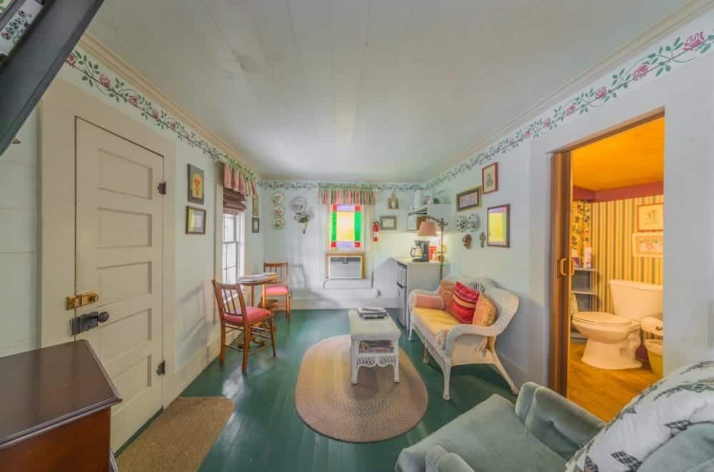 A living room with a couch , chair , table and a toilet.