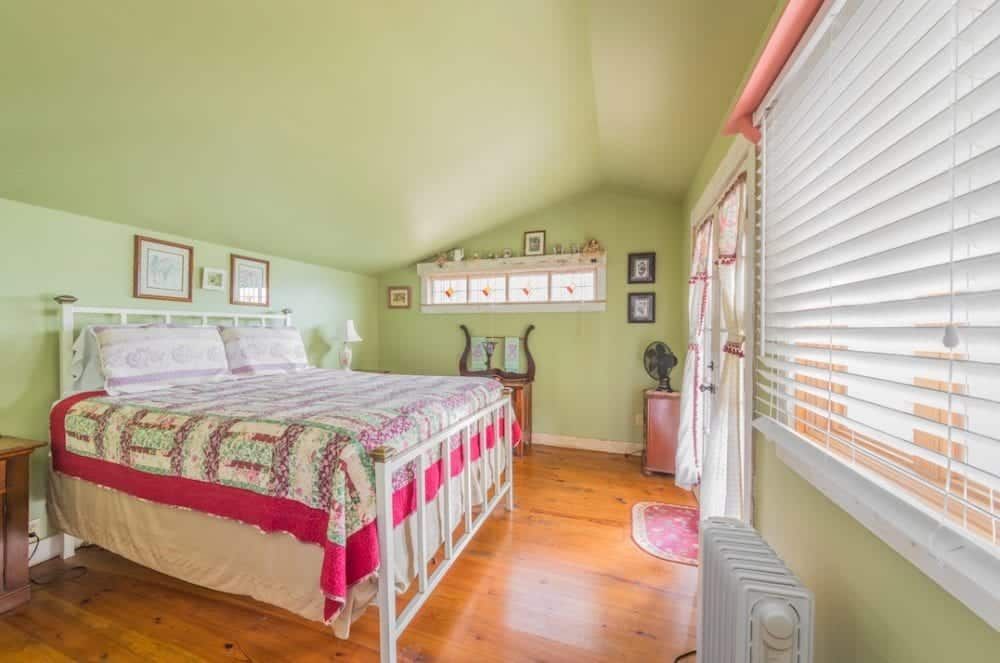 A bedroom with a bed , dresser , window and blinds.