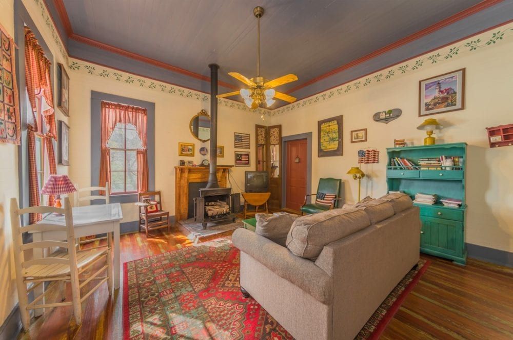 A living room with a couch , table , chairs and a ceiling fan.