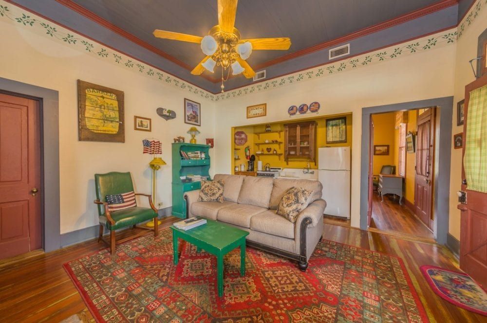 A living room with a couch , table , chairs and a ceiling fan.