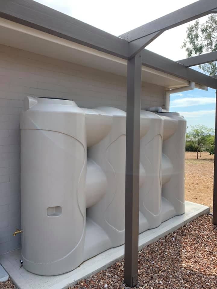 Two Water Tanks Are Sitting Next To Each Other In Front Of A House – Moore Creek, NSW - Thrift Plumbing Pty Ltd