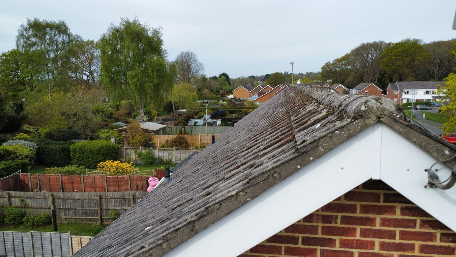 Rooftop view over a suburban neighborhood with trees, houses, and overcast sky