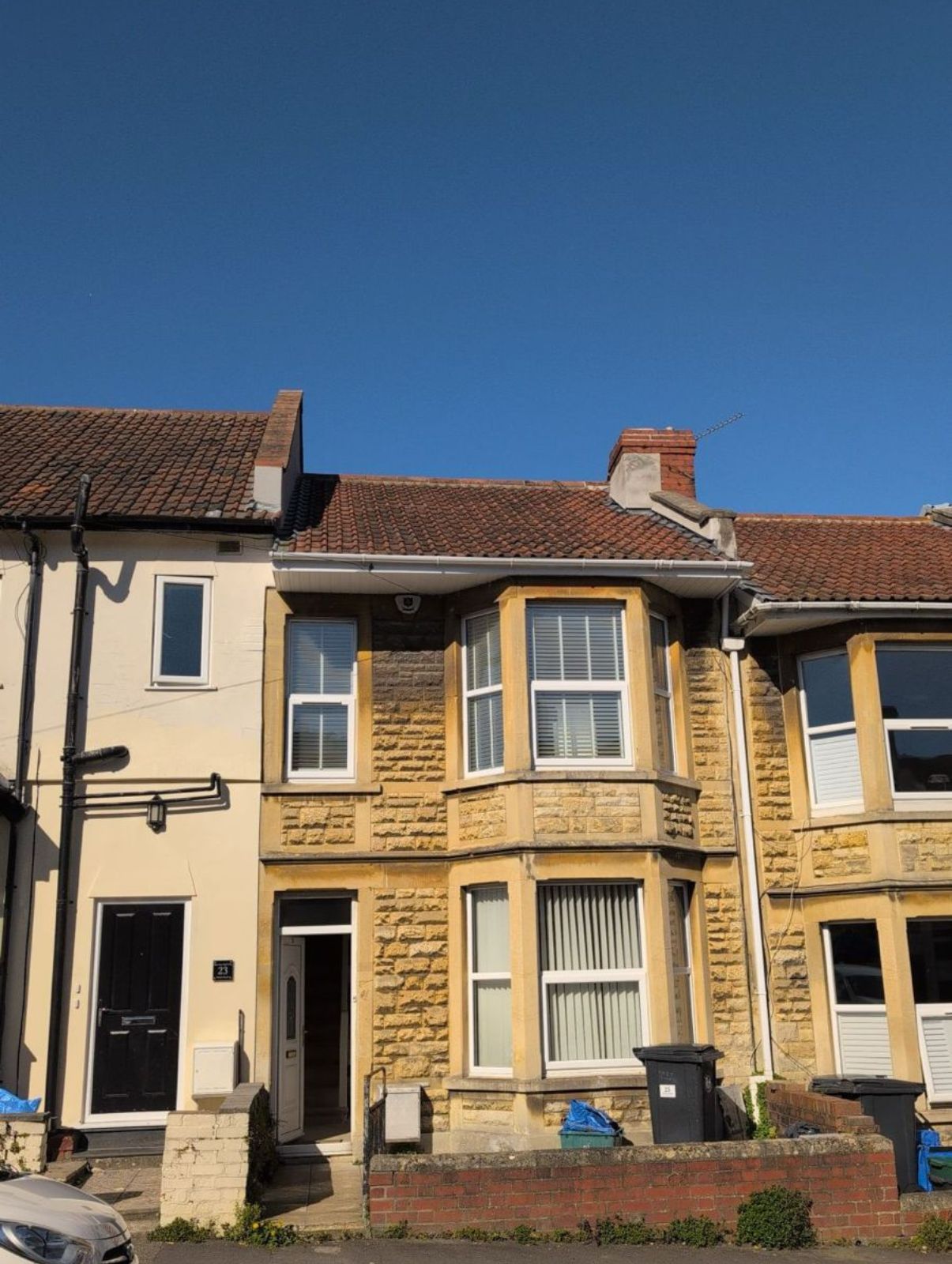 Row of terraced houses with a yellow brick facade under a clear blue sky