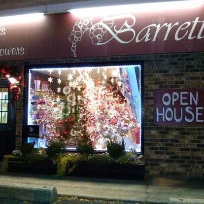 Exterior of Barretts Flowers store with illuminated window display and 