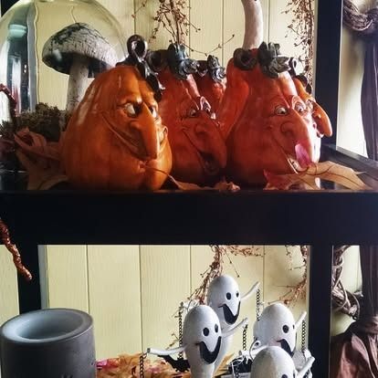 Halloween shelf decor with orange pumpkin figurines and ghost figures.