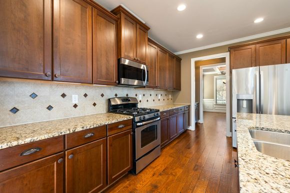 Kitchen with dark wood cabinets, stainless steel appliances, and granite countertops.