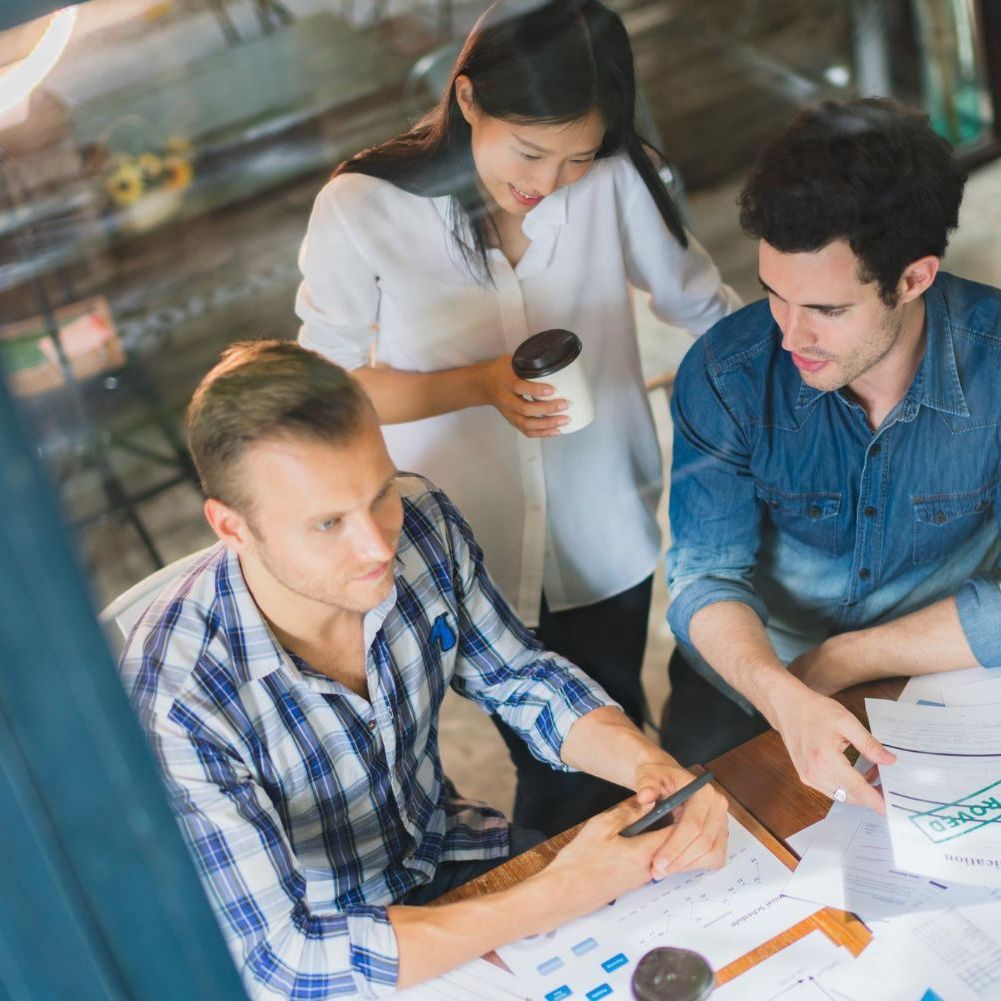 Three coworkers collaborating over documents.