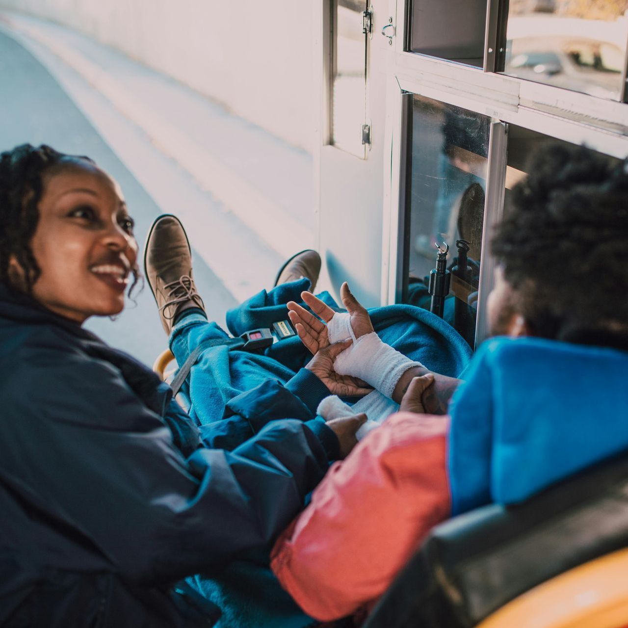 Paramedic tending to a patient with a bandaged wrist inside an ambulance.
