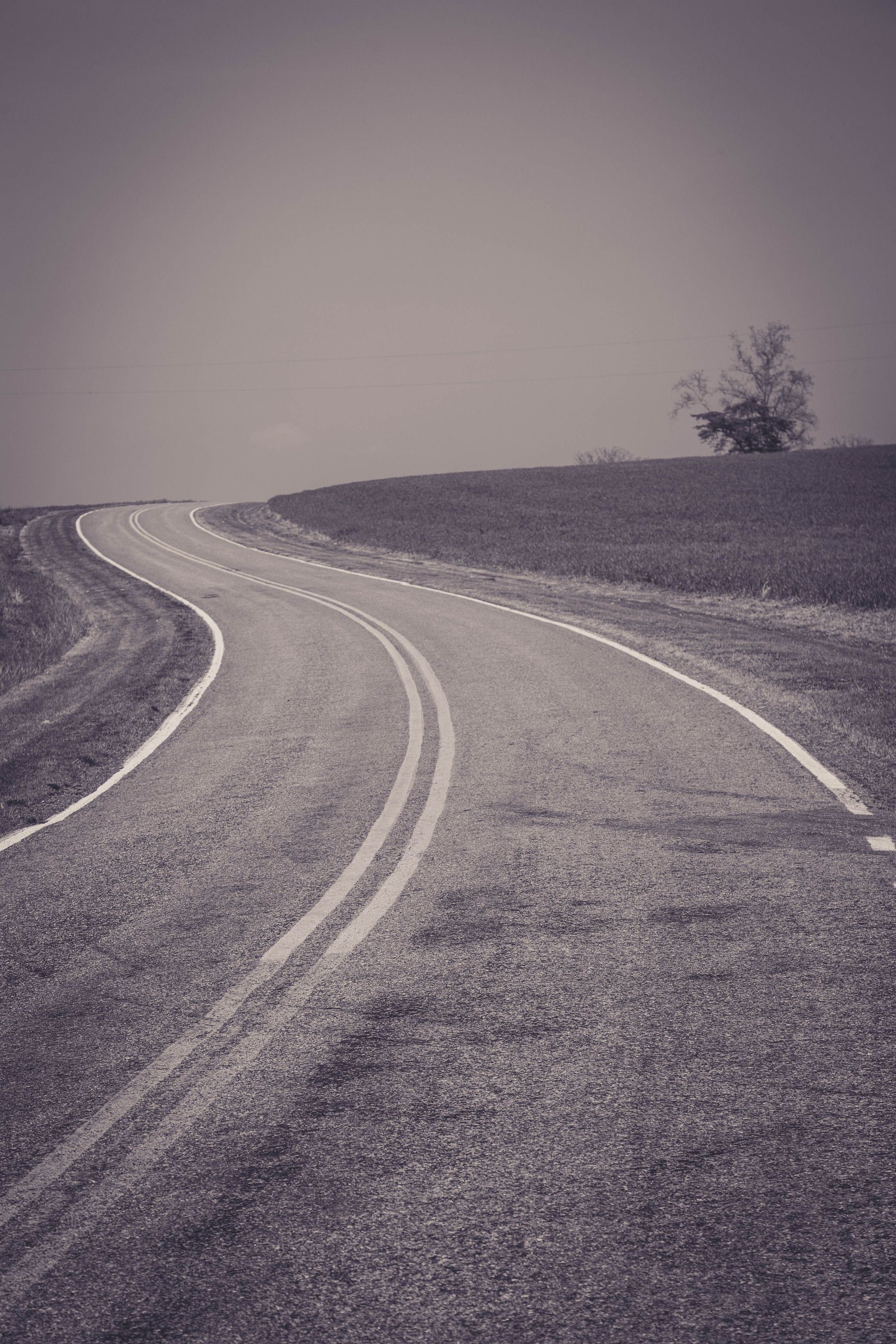 Winding gravel road with white lane markings stretching into a hazy landscape