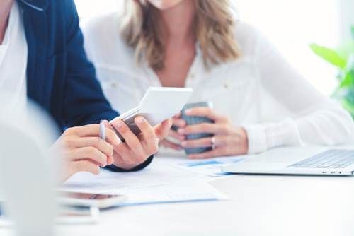 a man and a woman are sitting at a table looking at financial documents - commercial debt recovery.