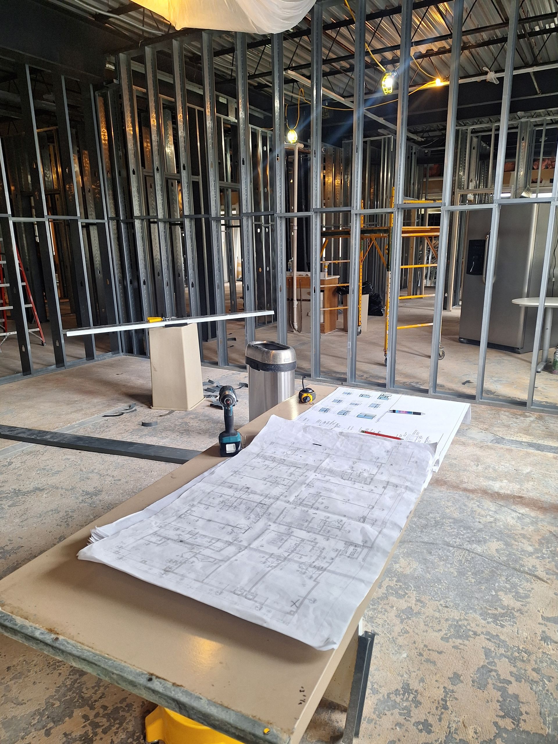 Interior view of a building under construction, showing metal stud framing for walls and ceiling.