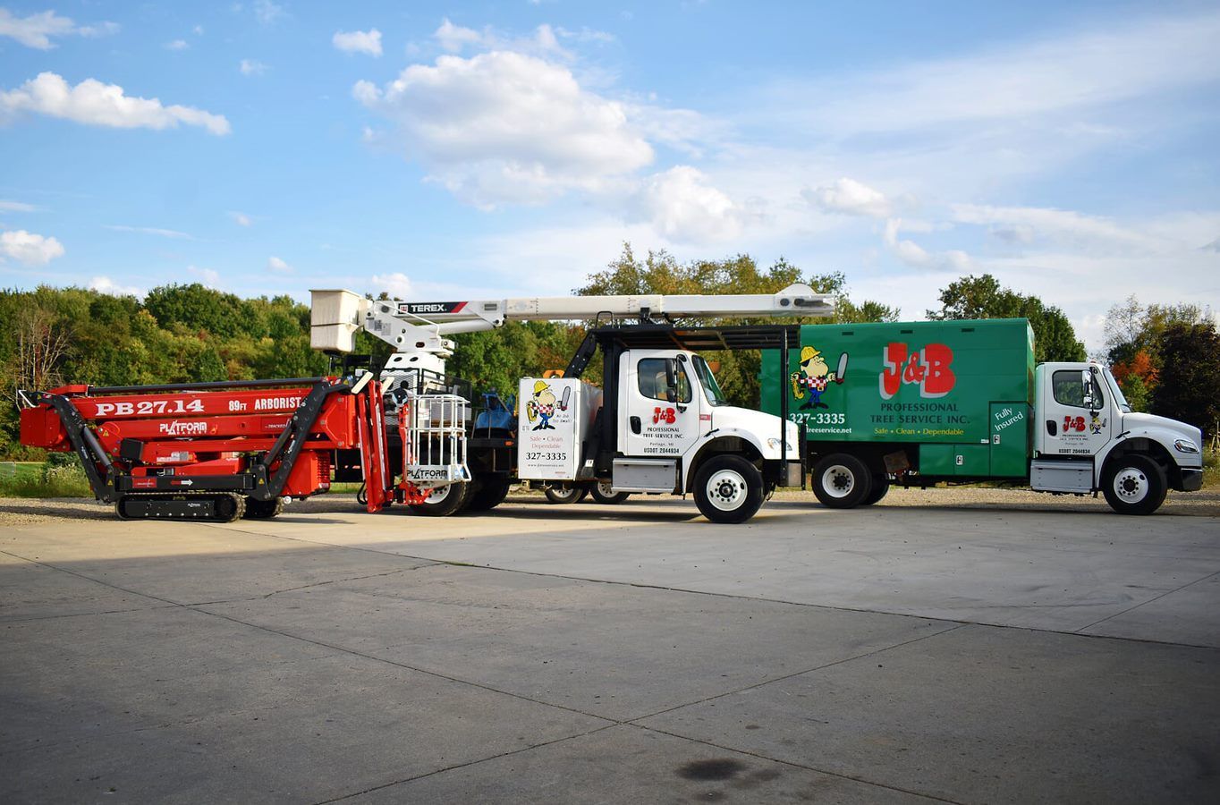 Two service trucks with a trailer on a gray paved area in a park. One truck has a lift, another has a large logo.
