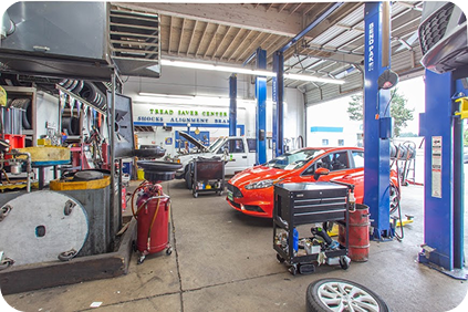 A garage with a lot of cars being worked on | TNT Tire Point S Auto Service