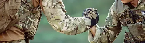 Two soldiers are shaking hands in a field. | TNT Tire Point S Auto Service