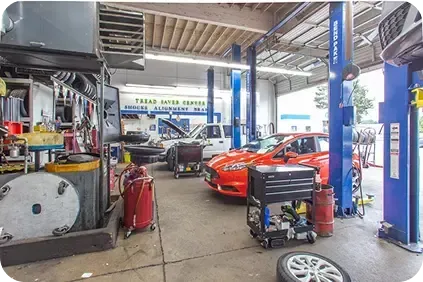 A garage with a lot of cars being worked on | TNT Tire Point S Auto Service