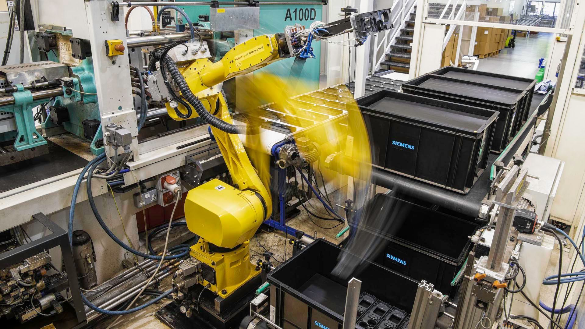 a moving robotic arm is working on a machine in a factory .