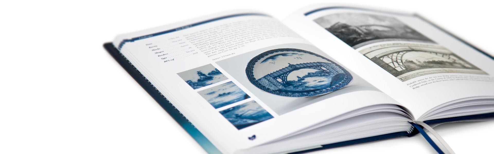a copy of the caughley blue and white pattern book is open to a page with a picture of the iron bridge on it