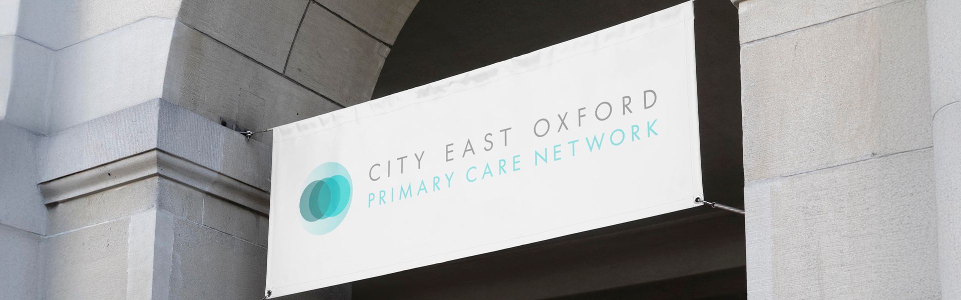 A white sign with a blue circle on it is hanging on a building.