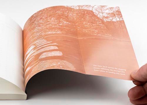 a person is holding a book open to a page with a picture of trees on it .