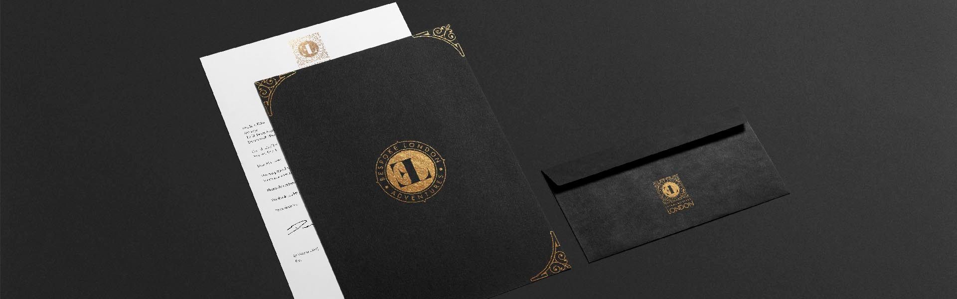 a black envelope and printed stationery with the extraordinary london logo printed in gold