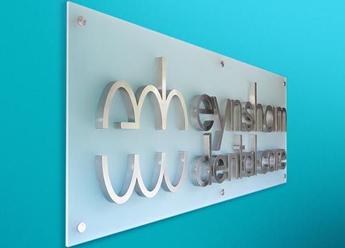 a sign for a dental office is hanging on a blue wall .