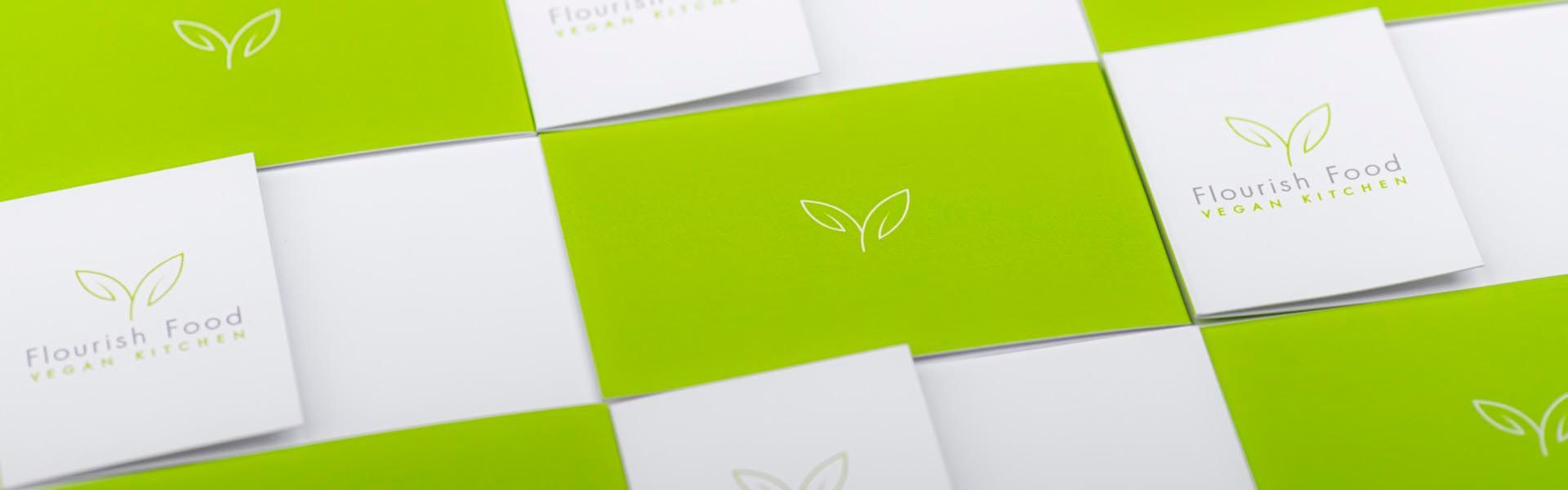 green and white brochures for flourish food vegan kitchen
