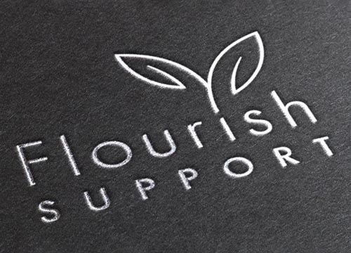 a close up of a flourish support logo on a black surface .