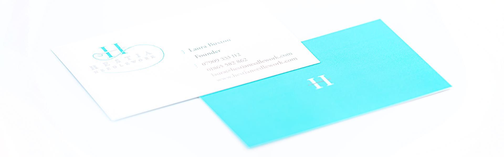 a blue and white business card for hestia needlework