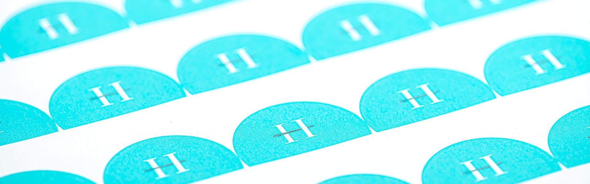 a row of blue circular stickers with the letter h on them