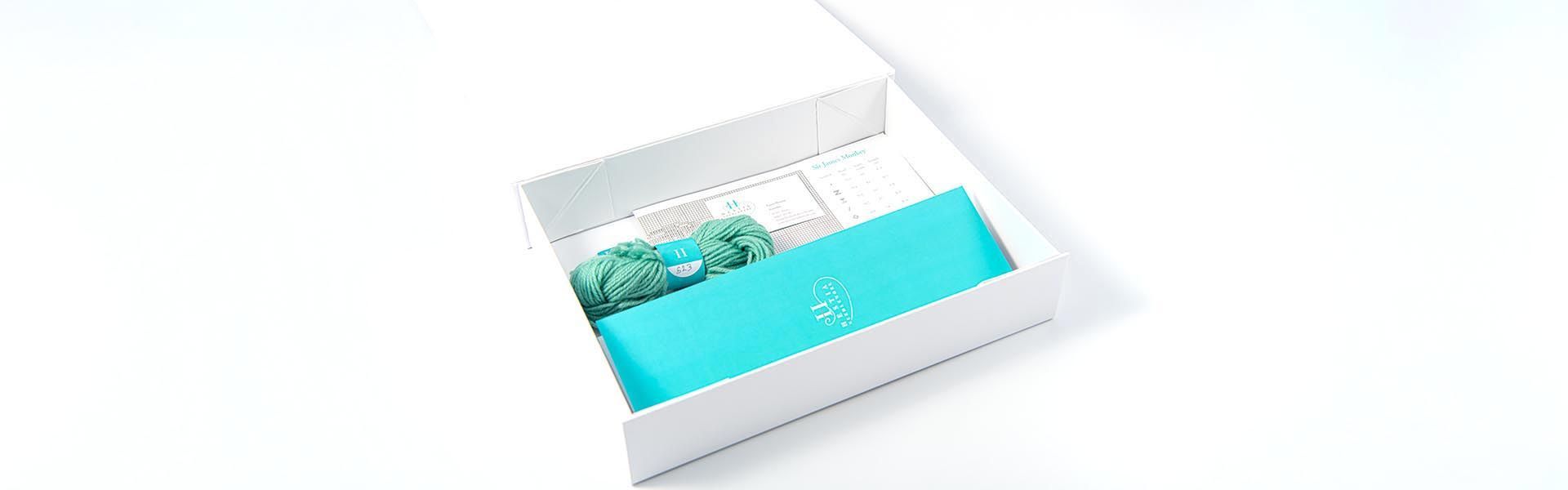 a white box with a blue brochure and wool sample inside of it